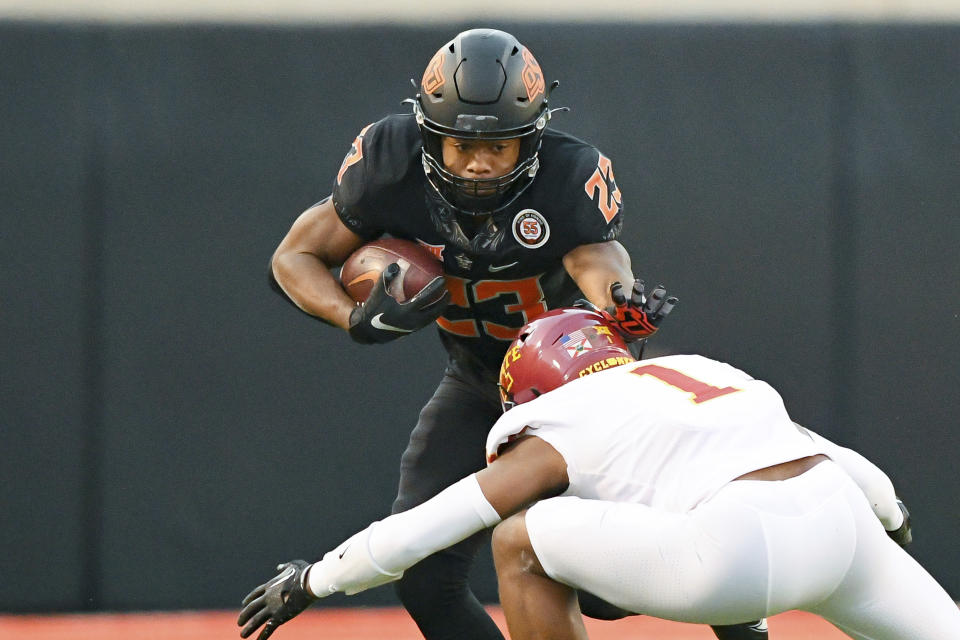 Oklahoma State running back Jaden Nixon (23) reaches out to block a tackle by Iowa State defensive back Anthony Johnson Jr. (1) during the second half of an NCAA college football game Saturday, Nov. 12, 2022, in Stillwater, Okla. (AP Photo/Brody Schmidt)