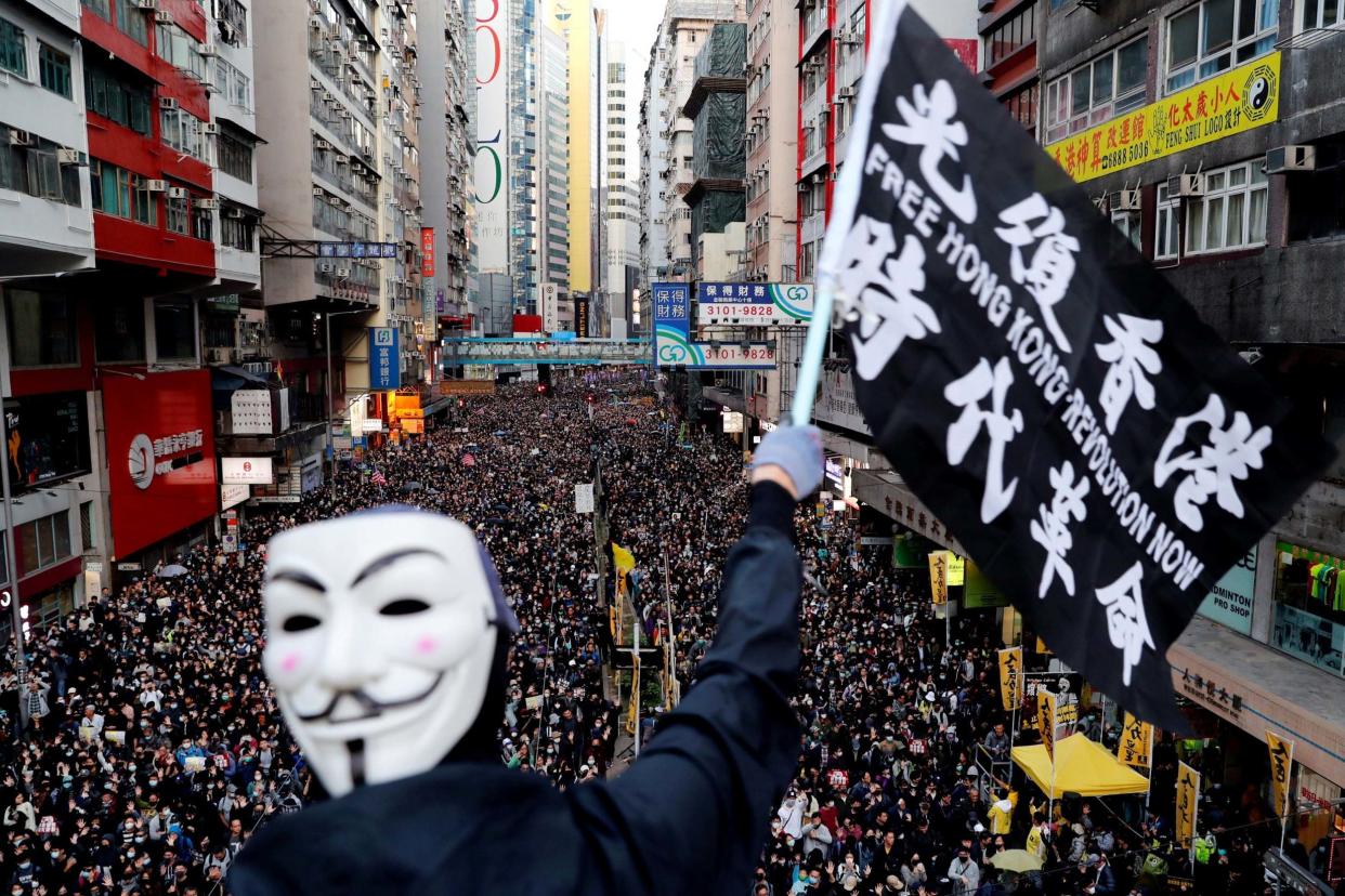 A protester wearing a Guy Fawkes mask waves a flag during a Human Rights Day march: REUTERS
