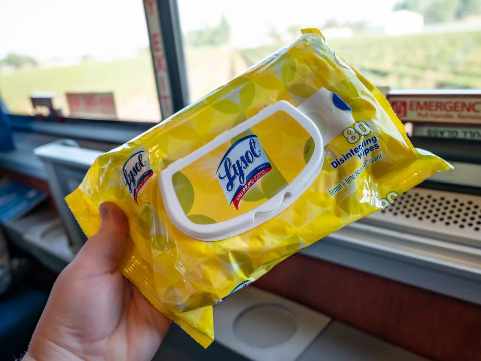 The writer holds a yellow package of Lysol wipes