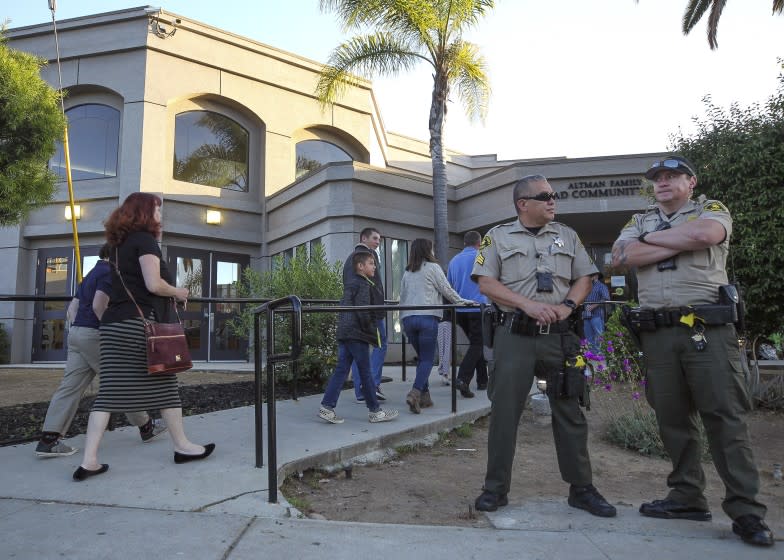 People enter Chabad of Poway for a Shabbat service as two Sheriff's deputies stand nearby on Friday, May 3, 2019 in Poway, California.