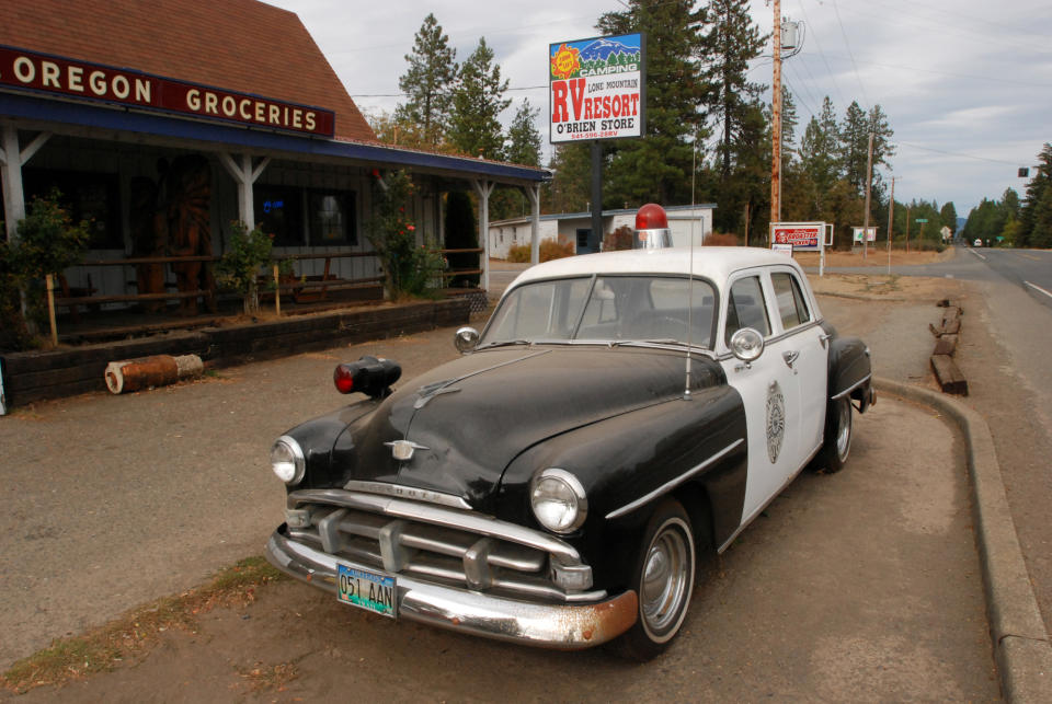 In this Oct. 12, 2012, photo, an old police car is permanently parked on the highway through O'Brien, Ore., where cuts to the sheriff's office have prompted some local residents to mount armed patrols to prevent crime. Members of the Citizens Against Crime group say they carry pistols only for protection, and are not vigilantes. Sheriff Gil Gilbertson says he is glad for the extra eyes and ears in the rural community, but warns that people could be sued for false arrest or shooting someone. (AP Photo/Jeff Barnard)