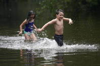 Marina Kingsmill and her brother Raylan play in the flooded street in front of their home after Tropical Storm Claudette passed through in Slidell, La., Saturday, June 19, 2021. The National Hurricane Center declared Claudette organized enough to qualify as a named storm early Saturday, well after the storm's center of circulation had come ashore southwest of New Orleans. (AP Photo/Gerald Herbert)