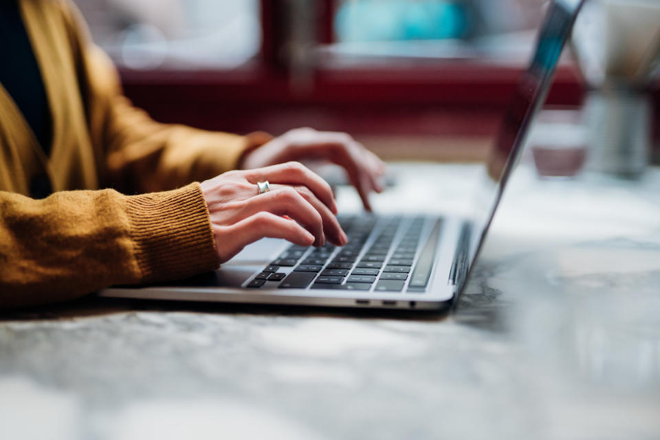 A hand typing at a laptop