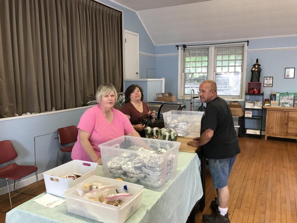 Taunton Area Community Table Volunteers, L-R Paula McGrath and Karen St. George talk with the agency's operation manager Leo Silvia while preparing meals.