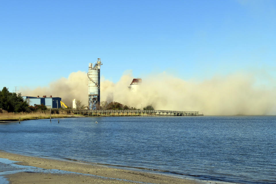 Debris and dust fill the air after smokestack at the former B.L. England power plant in Upper Township, N.J., was felled during a control demolition, Thursday, Oct. 26, 2023. The site will be redeveloped as a mixed use residential and commercial project, and a nearby electrical substation will be used to connect New Jersey's soon-to-come offshore wind farms with the electrical grid. (AP Photo/Wayne Parry)