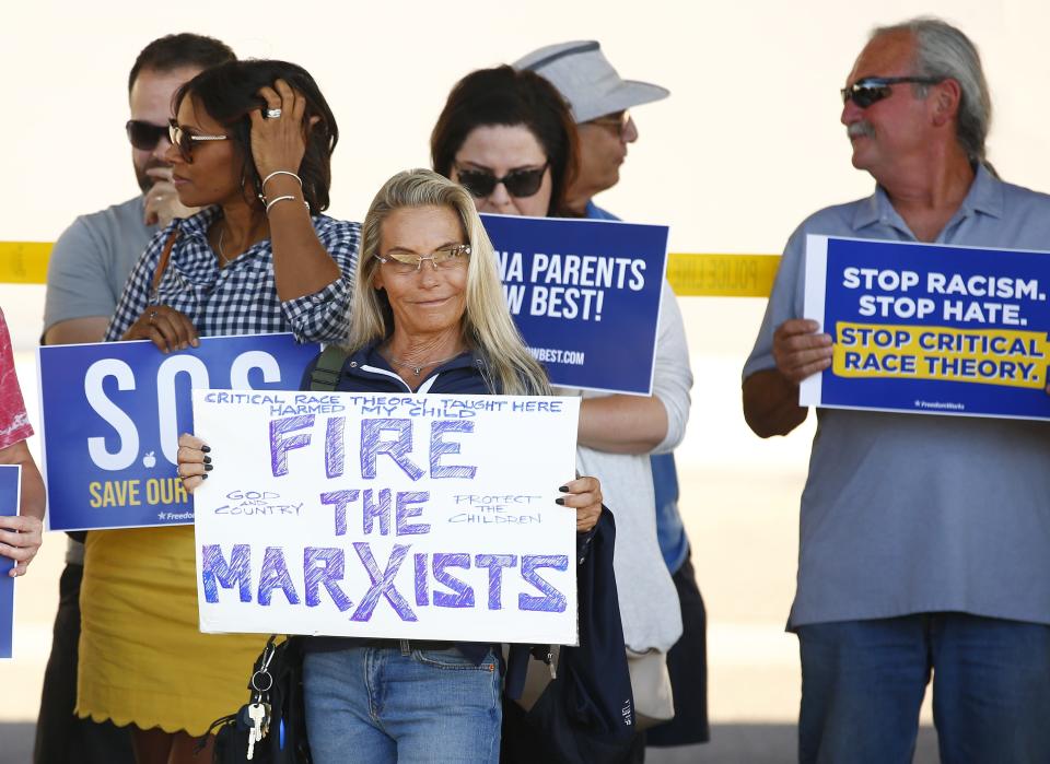 People pose with their signs for pictures during a protest against critical race theory by parents of Scottsdale Unified School District students at Coronado High School in Scottsdale on May 24, 2021.