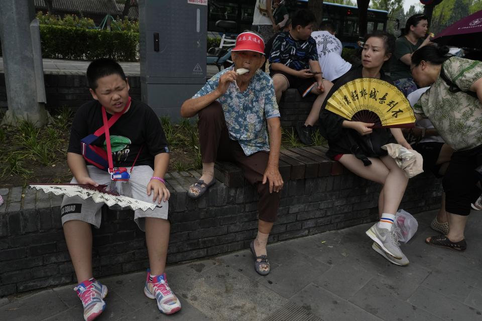 FILE - Tourists eat popsicle and fan themselves to cool off from the humid weather in Beijing, Aug. 9, 2023. UN weather agency says Earth sweltered through the hottest summer ever as record heat in August capped a brutal, deadly three months in northern hemisphere.(AP Photo/Ng Han Guan, File)