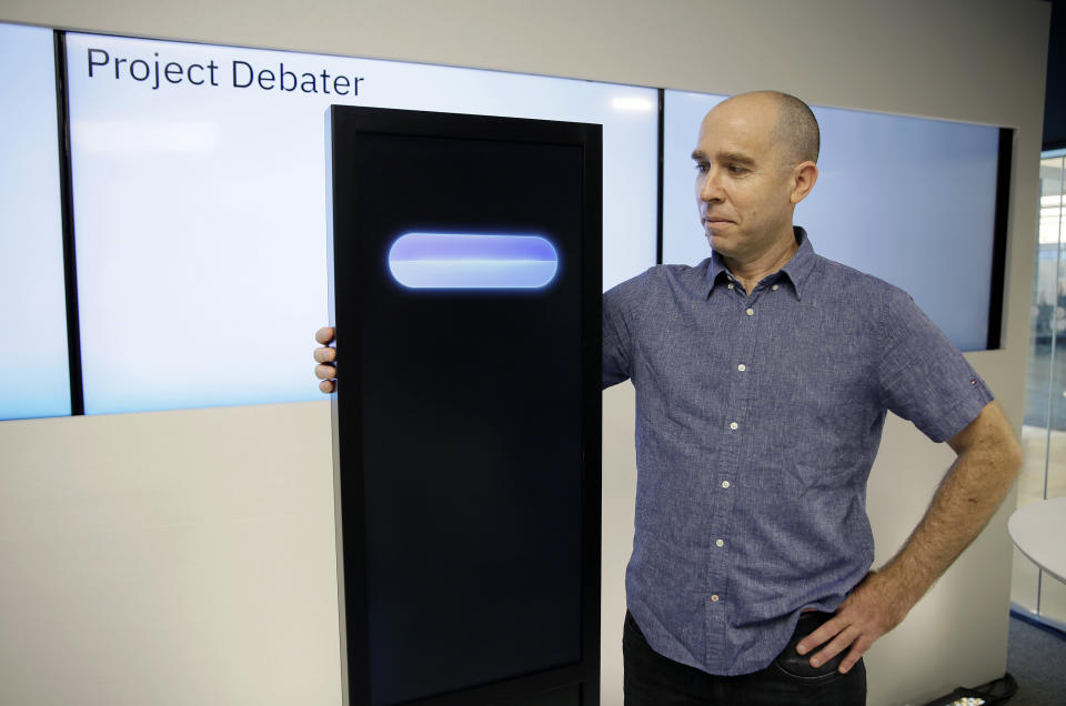 FILE - In this Monday, June 18, 2018 file photo, Dr. Noam Slonim, principal investigator, stands with the IBM Project Debater before a debate between the computer and two humans in San Francisco. Slonim put humor into the programming, figuring that a one-liner every now could help in a debate. But in initial internal tests, it backfired when the system gave a humorous remark at an inappropriate time and way. “We know that humor _ at least good humor _ relies on nuance and on timing,” Slonim said. “And these are very hard to decipher by an automatic system.” (AP Photo/Eric Risberg)