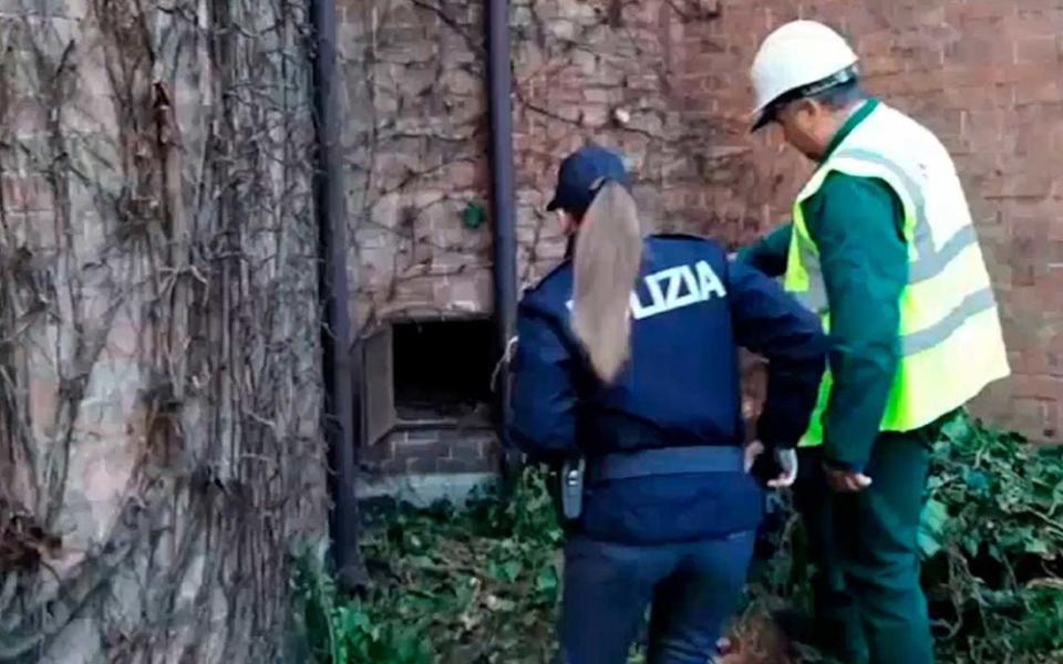 This image taken from a video distributed by Italian police shows an unidentified man showing a police officer a metal panel in which a painting was found, in Piacenza, northern Italy. A gardener at the Ricci Oddi modern art gallery in the northern city of Piacenza told Italian state TV on Tuesday that he was clearing ivy from the gallery's walls when he noticed a metal panel in which he found a bag inside a space within the walls. When the bag was opened it contained a painting that might be Klimt's 