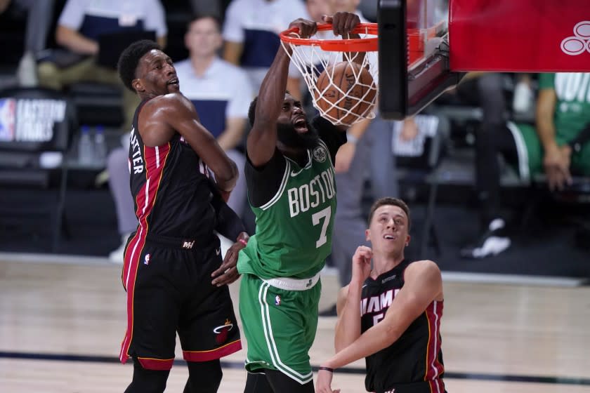 Boston Celtics guard Jaylen Brown (7) dunks the ball between Miami Heat's Bam Adebayo, left, and Duncan Robinson.