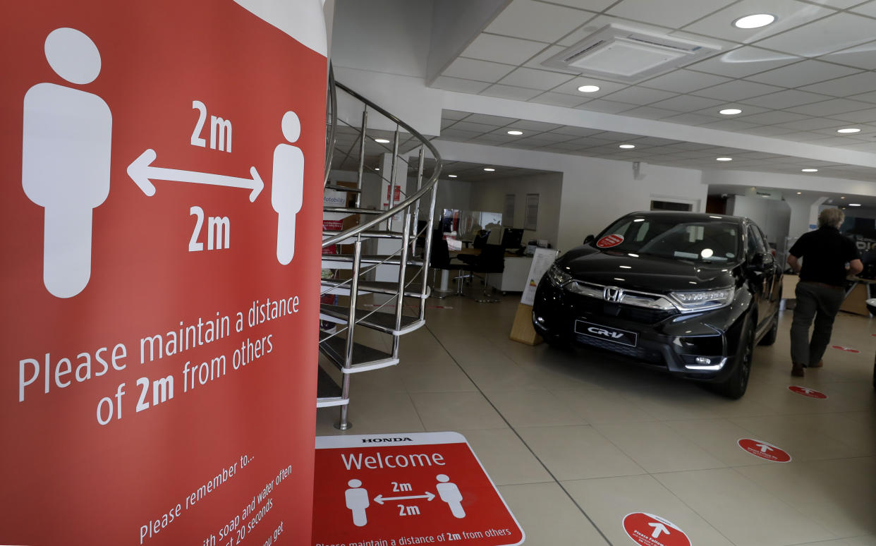 Social distancing signs at the Trident Honda car dealership, Ottershaw in Surrey, England, Friday, May 29, 2020. Lockdown restrictions are being lifted in England with car sales showrooms allowed to reopen from Monday. The Trident Honda showroom has strict social distancing measures in place with reduced cars on show to allow distancing and rigorous cleaning schedules arranged. (AP Photo/Kirsty Wigglesworth)