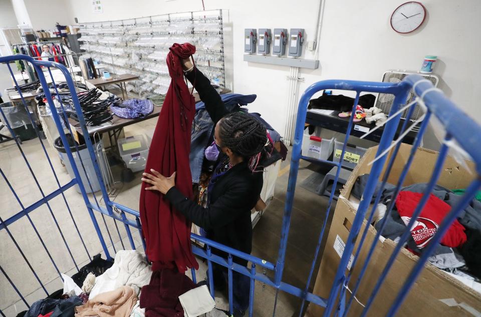 Latasha Lee, a wares processor at the Goodwill Store on Waterloo Road, sorts clothing items that will go to the store and for the outlet, where items are sold by the pound.