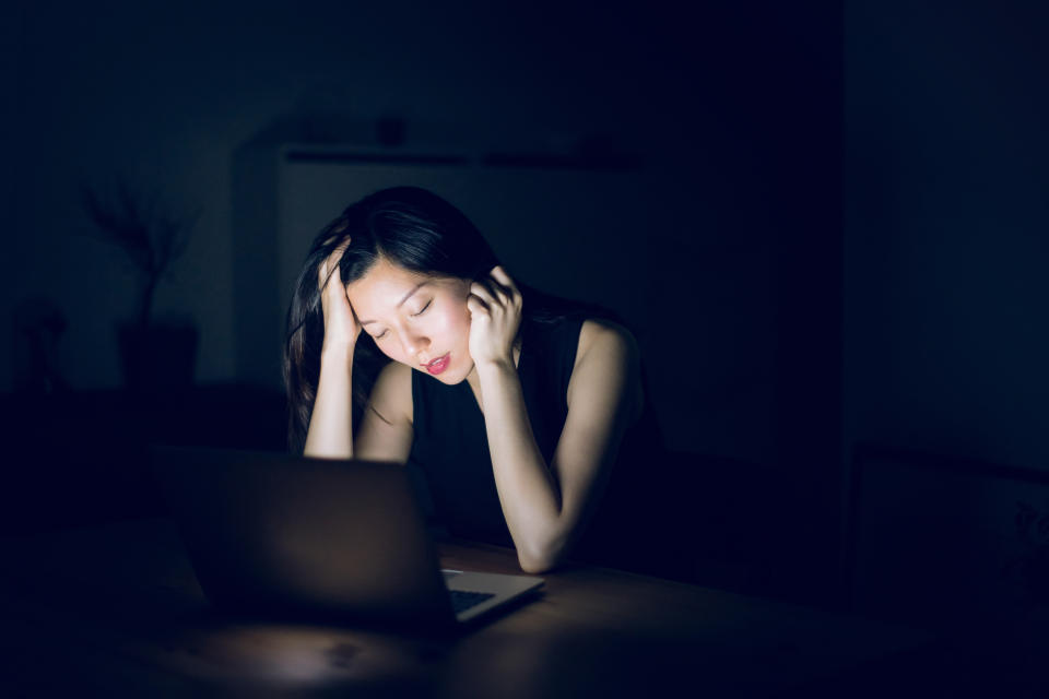 Tired and sleepy woman working in front of laptop till late in office