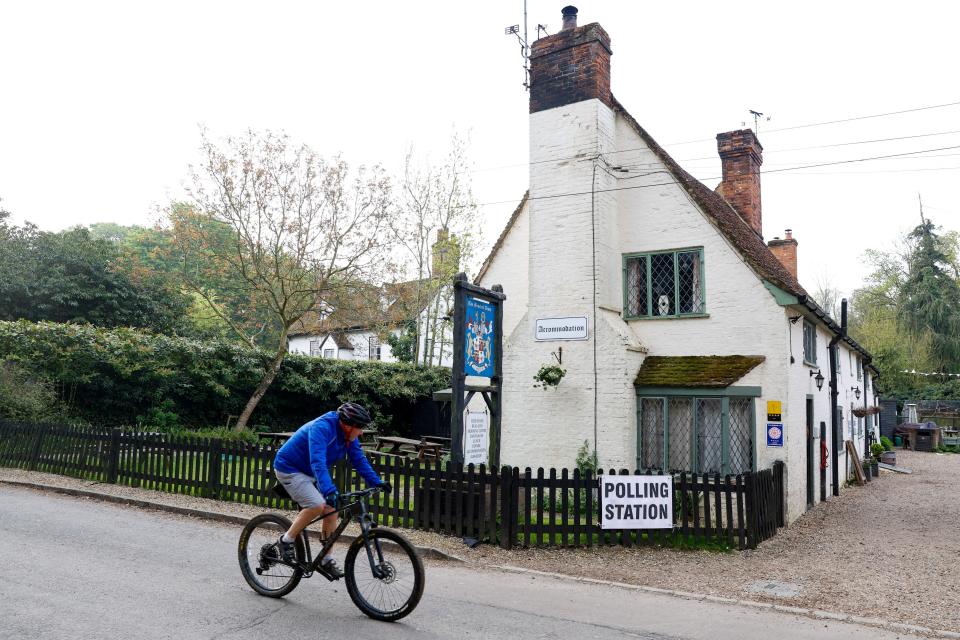 A man rides a bicycle near The Brocket Arms pub which is acting as a polling station for local elections in Ayot St Lawrence, Britain (REUTERS)