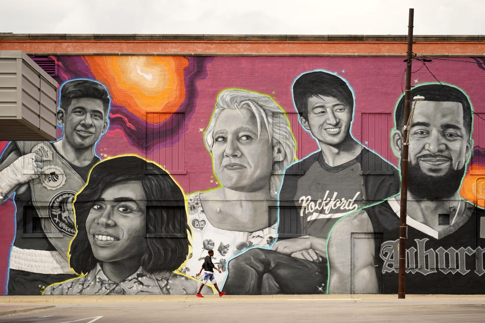 A man walks past the commissioned mural titled We are Rockford, by Artist, Ryan "Stuk One" Lape of famous Rockford, Ill., natives Monday, Sept. 20, 2021, in Rockford. Pictured from left are, Angel Martinez, Golden Gloves Champion; Michelle Williams, Best selling author and mental health advocate, former member of Destiny's Child; Sara Dorner, President Rockford United Labor, first woman President of RUL; Bing Liu, Oscar-winning director, and Fred VanVleet: NBA superstar. The money flowing to cities and states from the American Rescue Plan is so substantial and can be used for so many purposes that communities across the U.S. are trying out new, longer-term ways to fix what’s broken in their cities. (AP Photo/Charles Rex Arbogast)