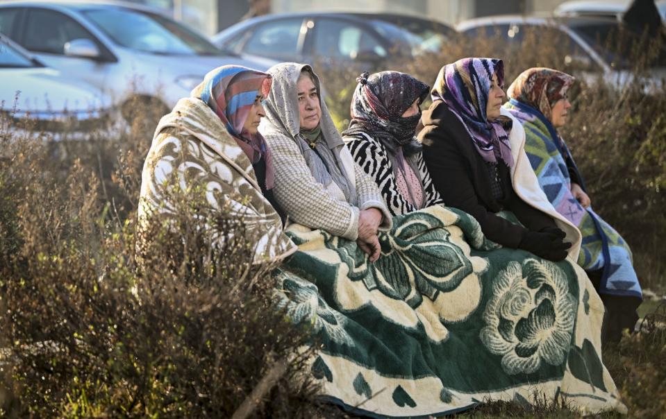  Women sit outside while search and rescuw team work in Hatay - Anadolu