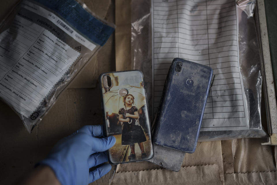 Un agente de policía muestra uno de los celulares hallados en el interior de una embarcación mauritana, en la comisaría de policía de Scarborough, en Trinidad y Tobago, el 21 de enero de 2022. (AP Foto/Felipe Dana)