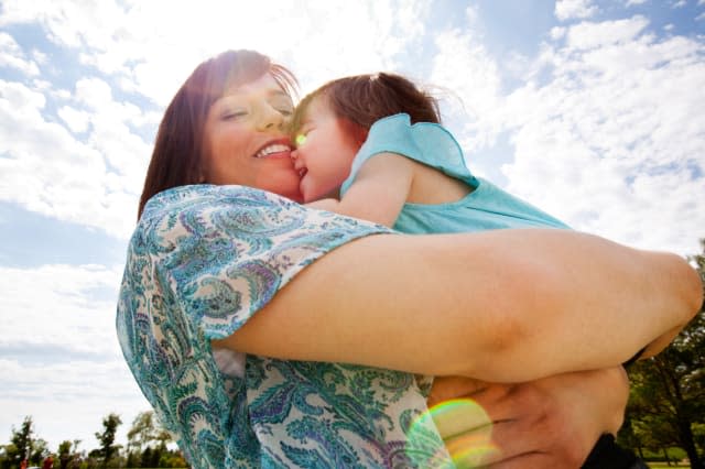 Happy smiling mother giving daughter a big hug outdoors