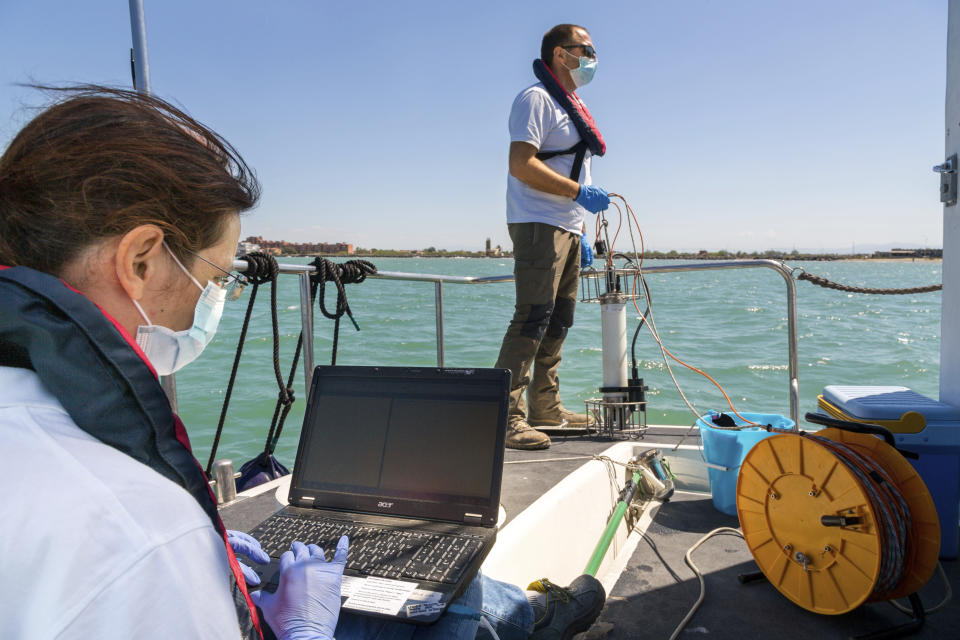 In this picture taken on Thursday, May 21, 2020, Italian Lazio region's environmental agency biologists Salvatore De Bonis, right, and Valentina Amorosi show how they perform tests on sea water during an interview with The Associated Press on a Coast Guard boat off Fiumicino, near Rome. Preliminary results from a survey of seawater quality during Italy’s coronavirus lockdown indicate a sharp reduction in pollution from human and livestock waste in the seas off Rome. Authorities stressed it was too soon to give the lockdown sole credit for the change. (AP Photo/Domenico Stinellis)