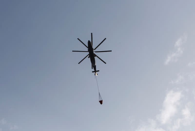Helicopter assists transporting water following a wildfire in Bejaia