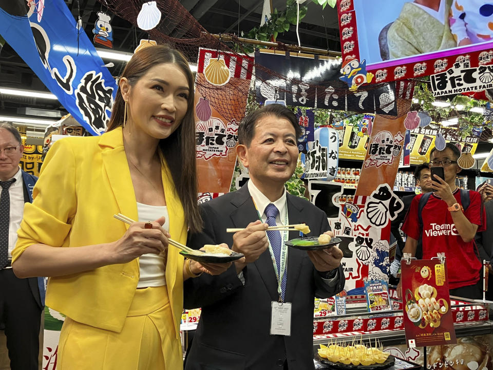Japanese Agriculture Minister Ichiro Miyashita, right, and Malaysian celebrity Amber Chia attend an event at Japanese store, Don Don Donki in Kuala Lumpur Wednesday, Oct. 4, 2023 to promote the safety and deliciousness of Japanese scallops to shoppers. Japan hopes to resolve the issue of China's ban on its seafood within the scope of the World Trade Organization ambit and will hold food fairs overseas to bolster seafood exports amid safety concerns over the release of treated water from the Fukushima Daiichi nuclear plant, Miyashita said Wednesday. (AP Photo/Eileen Ng)