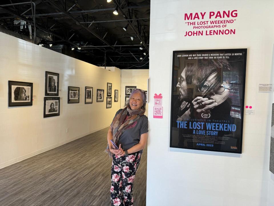 May Pang poses with snapshots that are part of the popup exhibit “The Lost Weekend – the Photography of May Pang.”