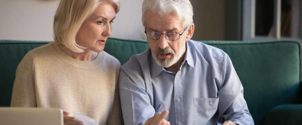 Concerned elderly husband and wife use calculator machine calculate household expenditures