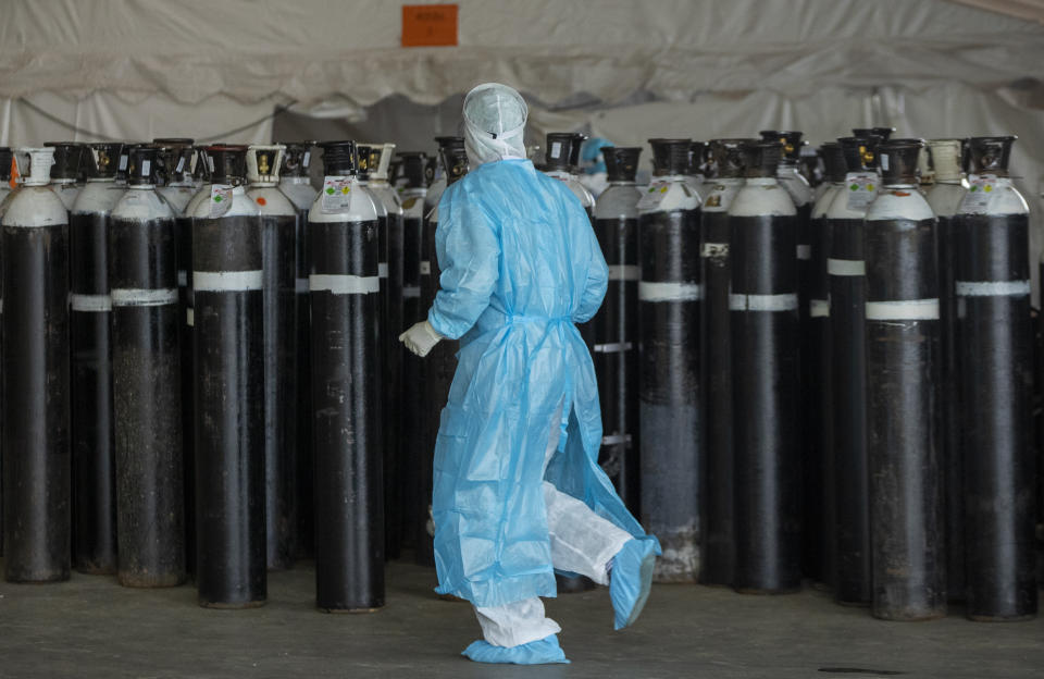 FILE - In this Jan. 11, 2021, file photo, a health worker in a protective suit runs past oxygen cylinders in a makeshift emergency unit for COVID-19 patients at Steve Biko Academic Hospital in Pretoria, South Africa. In South Africa, with by far the largest number of COVID-19 cases and deaths in Africa, officials warn of a new surge as the Southern Hemisphere’s winter approaches. ​(AP Photo/Themba Hadebe, File)