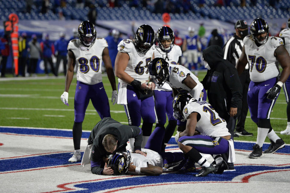 A trainer checks on Baltimore Ravens quarterback Lamar Jackson, below, after he was injured during the second half of an NFL divisional round football game against the Buffalo Bills Saturday, Jan. 16, 2021, in Orchard Park, N.Y. (AP Photo/Adrian Kraus)