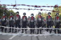 FILE - Police stand guard behind barbed wire as they attempt to stop protesters outside Union Election Commission office in Naypyitaw, Myanmar on Nov. 11, 2020. Ousted Myanmar leader Aung San Suu Kyi is the daughter of the country’s independence hero, Gen. Aung San, who was assassinated in 1947, less than six months before the country, then called Burma, became independent from Britain. Suu Kyi moved to New Delhi in 1960 when her mother was appointed ambassador to India and then spent most of her young adult life in the United States and England. Her career in politics began in 1988. (AP Photo/Aung Shine Oo, File)