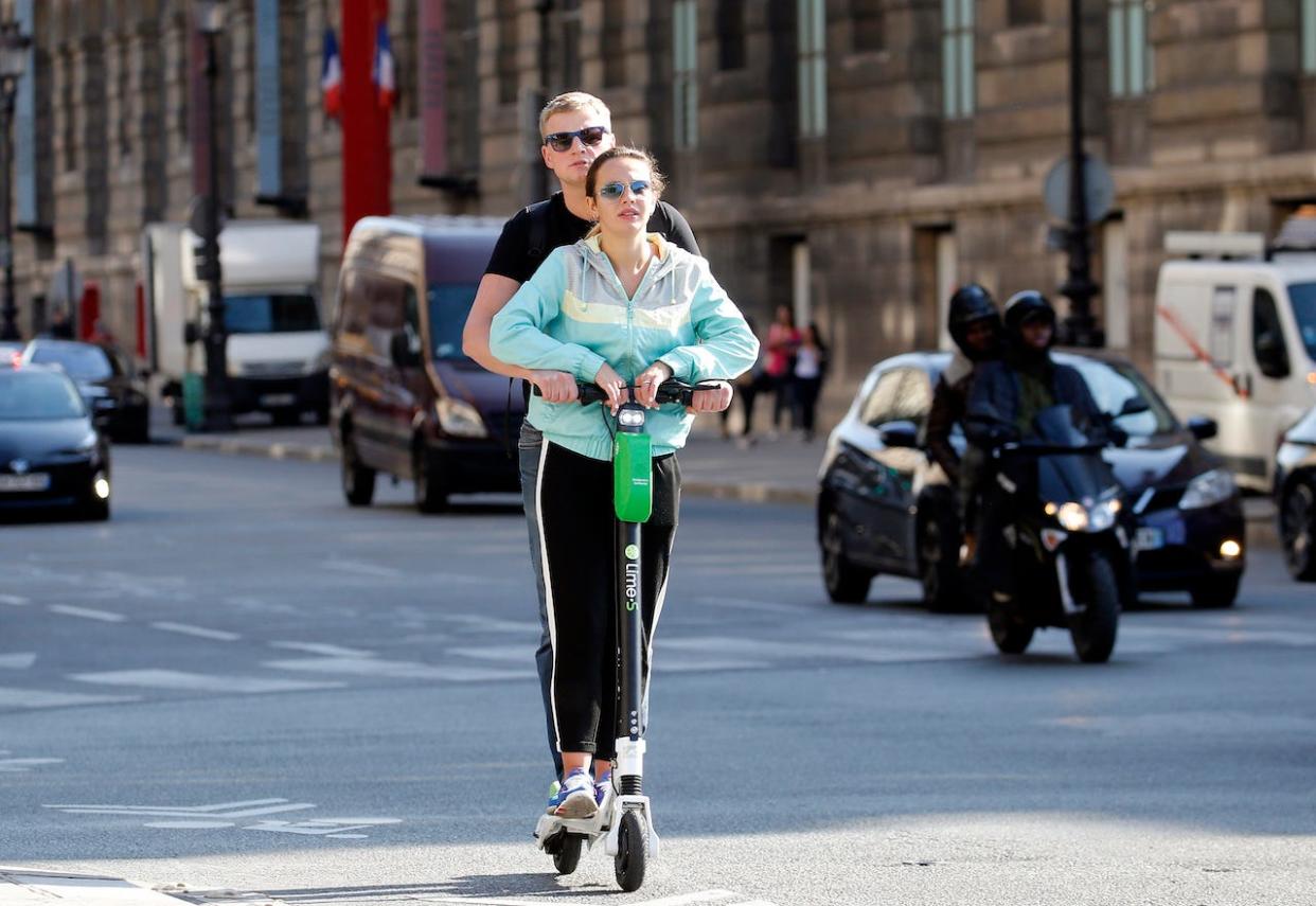 Tourists ride an electric scooter Lime-S from the bike sharing service company 'Lime' on October 09, 2018 in Paris, France.