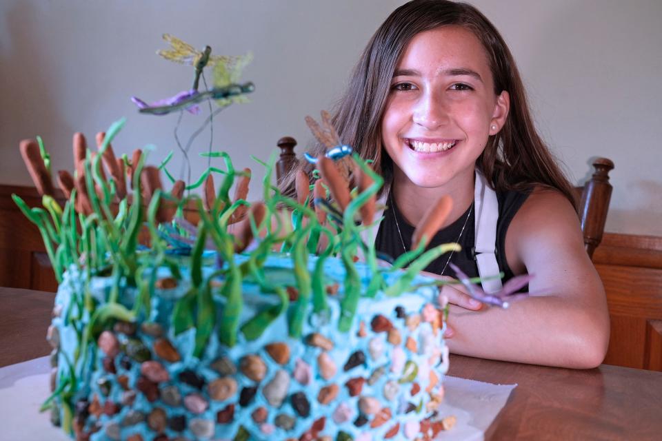 Elena Scray, 12, poses with her dragonfly-inspired cake at her grandmother's house in Pewaukee on July 20, 2023. The 12-year-old has won multiple ribbons from Wisconsin State Fair for her bakery entries.
