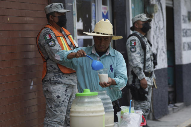 A vendor sells drinks as ash from the Popocatepetl volcano blankets the streets in Santiago Xalitzintla, Mexico, Monday, May 22, 2023. The volcano´s activity has increased over the past week. Evacuations have not been ordered, but authorities are preparing for that scenario and telling people to stay out of 7.5-mile (12-kilometer) radius around the peak. (AP Photo/Marco Ugarte)