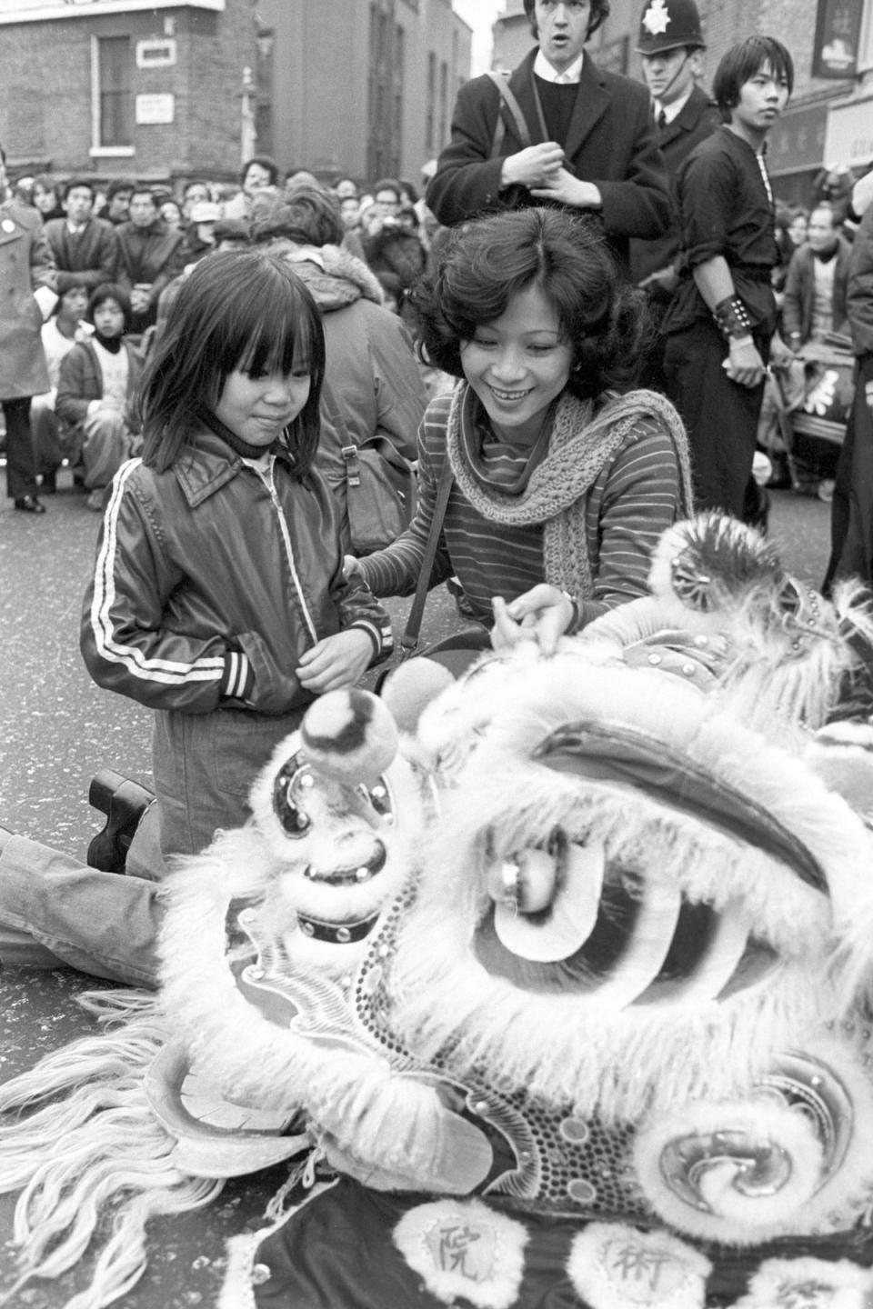 Czarine Chang (right) and Fook Ho Tao, 8, with a Chinese lion head mask during the 1978 Chinese New Year celebrations in London's Soho (PA )