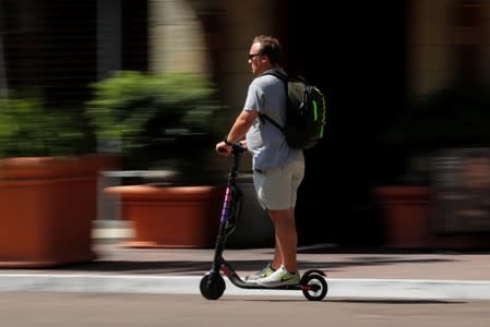 A man travels along a street atop an electric scooter in downtown San Diego , California