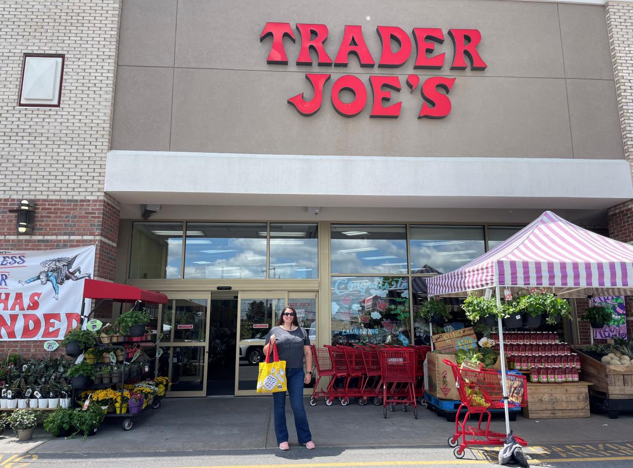 the writer standing outside of trader joe's with a bag