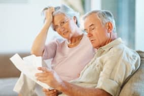 BHYT6R Elderly man with his wife going through documents on couch. Image shot 2009. Exact date unknown. Mistakes Retirees Make b