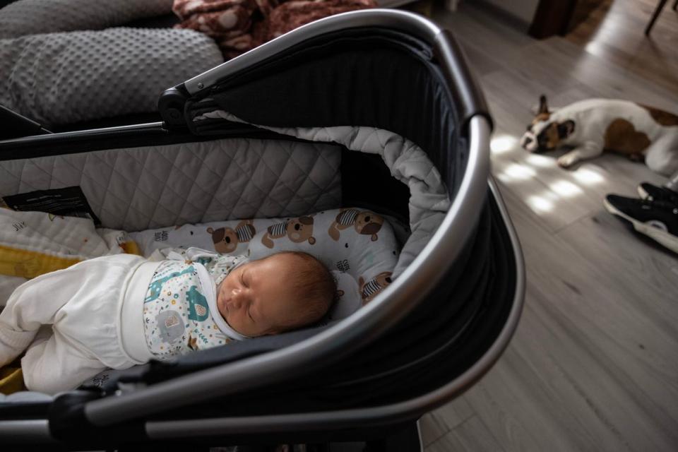 A baby sleeps in a baby carriage next to his parents in the village of Pokashchiv in Lutsk Oblast, Ukraine, on Aug. 15, 2023. (Paula Bronstein /Getty Images)