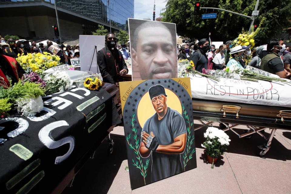 Pastor Eddie Anderson, center, of McCarty Memorial Church, stands behind caskets and an image of George Floyd, Monday, June 8, 2020, in Los Angeles during a protest over the death of Floyd on May 25 after he was restrained by Minneapolis police.