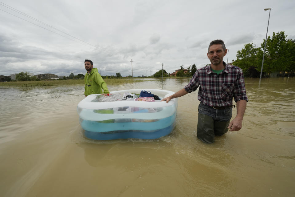 People use a plastic portable pool to carrie bags and personal effects in a flooded road of Lugo, Italy, Thursday, May 18, 2023. Exceptional rains Wednesday in a drought-struck region of northern Italy swelled rivers over their banks, killing at least eight people, forcing the evacuation of thousands and prompting officials to warn that Italy needs a national plan to combat climate change-induced flooding. (AP Photo/Luca Bruno)