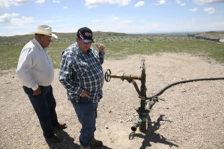 Two workers look at a gas well on the Crow Nation reservation near Crow Agency, Montana, May 30, 2008. REUTERS/Adam Tanner