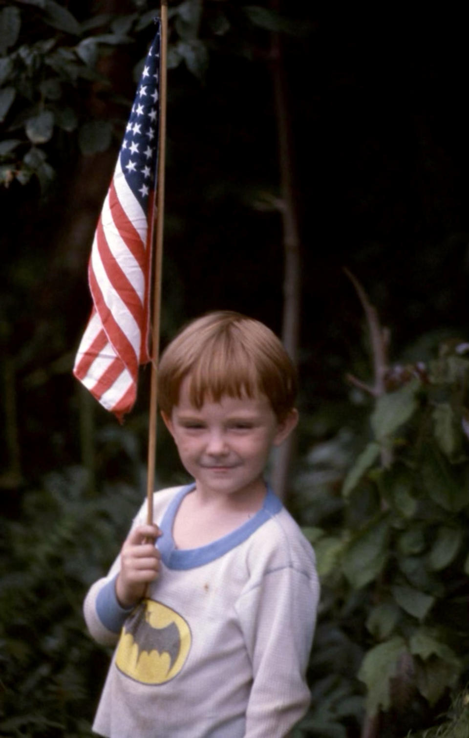 Image: Derek Scott as a young boy holding an American flag. (Courtesy Derek Scott)