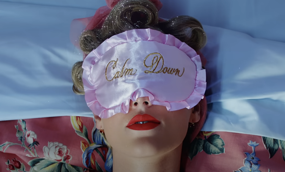 Person wearing a sleep mask with 'Calm Down' text, lying down with eyes closed