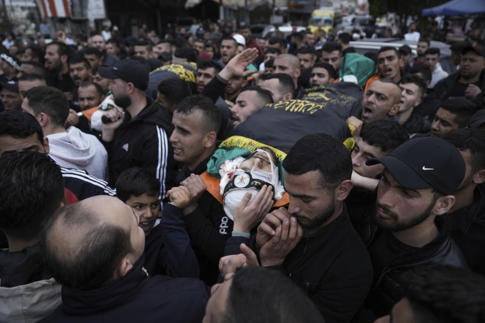 Mourners carry the bodies of three Palestinian militants, draped in the flag of the Islamic Jihad militant group, during their funeral in the West Bank city of Jenin, Thursday, March 9, 2023. Palestinian officials say at least three Palestinian militants were killed after Israeli security forces entered a village in the northern occupied West Bank. The Israeli Police said Thursday that troops carried out a raid in Jaba to apprehend suspects wanted for attacks on Israeli soldiers in the vicinity. The three militants killed included the head of a local Palestinian militant group. (AP Photo/Nasser Nasser)