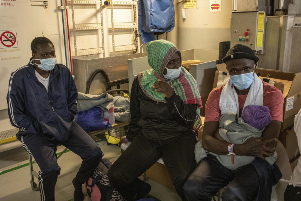 Migrants sit on the deck before being disembarked from the Norway-flagged Geo Barents rescue ship carrying 572 migrants, in Catania's port, Sicily, southern Italy, Sunday, Oct. 6, 2022. The Geo Barents, and the German-flagged Humanity1 have been allowed to disembark what the Italian authorities defined "vulnerable people" and minors, while other two ships carrying rescued migrants remained at sea. (AP Photo/Massimno Di Nonno)
