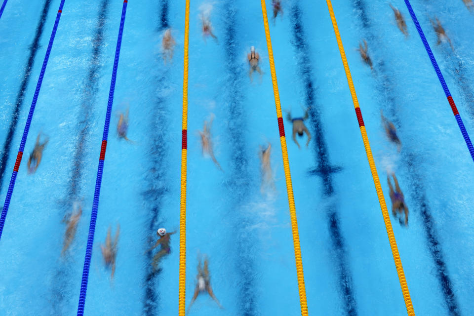 FILE - In this July 25, 2021, file photo, swimmers warm up before competition at the 2020 Summer Olympics in Tokyo. The price tag for the Tokyo Olympics is $15.4 billion. Tokyo built eight new venues. The two most expensive were the National Stadium, which cost $1.43 billion, and the new aquatic center, priced a $520 million. (AP Photo/David J. Phillip, File)