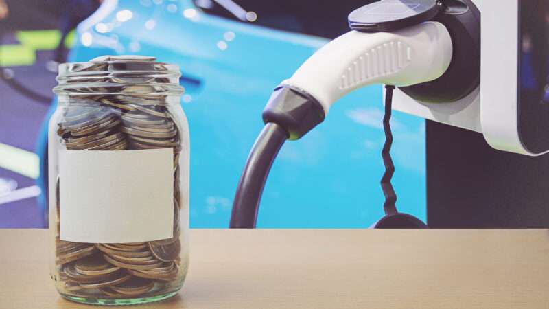 A jar full of coins alongside an electric vehicle and charger.