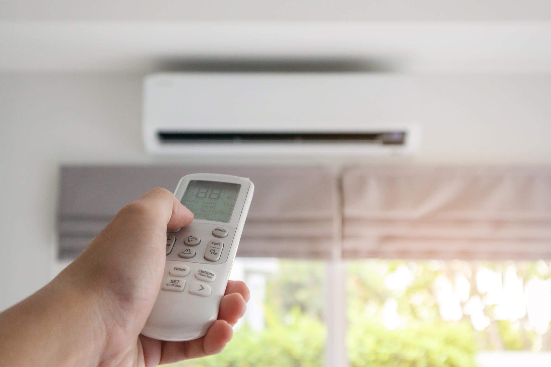 Hand with remote control directed on air conditioner