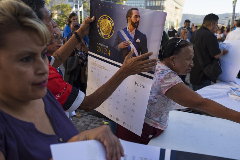 People receive calendars featuring El Salvador's President Nayib Bukele as supporters campaign for his re-election in San Salvador, El Salvador, Wednesday, Jan. 31, 2024. El Salvador will hold a presidential election on Feb. 4. (AP Photo/Moises Castillo)