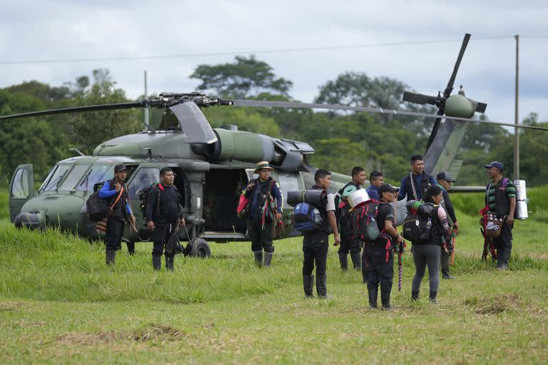 Hombres indígenas esperan para abordar un helicóptero en una base militar en Calamar, Colombia, el martes 23 de mayo de 2023, para ayudar en la búsqueda de cuatro niños desaparecidos después de un accidente aéreo. El presidente colombiano, Gustavo Petro, anunció el viernes 9 de junio de 2023 que los cuatro menores habían sido encontrados con vida tras 40 días en la selva. (AP Foto/Fernando Vergara)